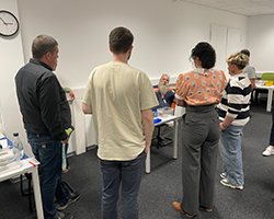 lernen erleben-Menschen stehen um Tisch